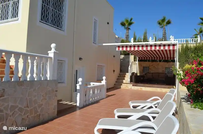 Jardín en el lateral de la casa con sofá y tumbonas.