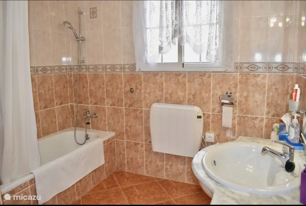 Badezimmer neben dem zweiten Schlafzimmer. Geräumiges Zimmer mit Toilette, Badewanne und Dusche sowie Waschbecken mit Spiegel