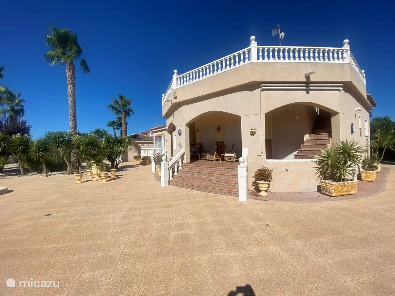 Die Vorderseite der Villa mit überdachter Veranda und Solariumbalkon im ersten Stock