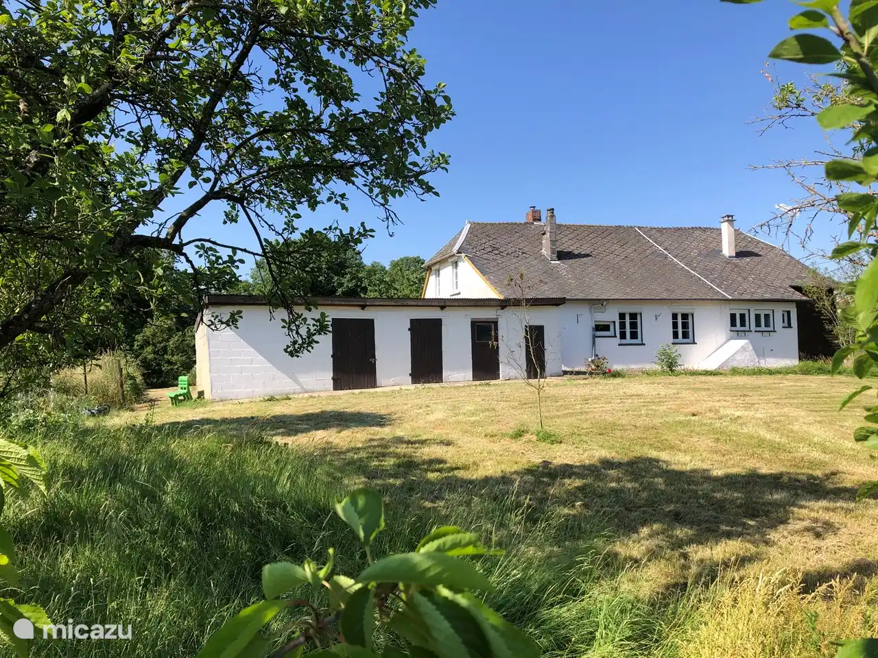 L'arrière de la maison, incluant une partie du jardin. Le jardin entoure la maison et est entièrement clôturé.
