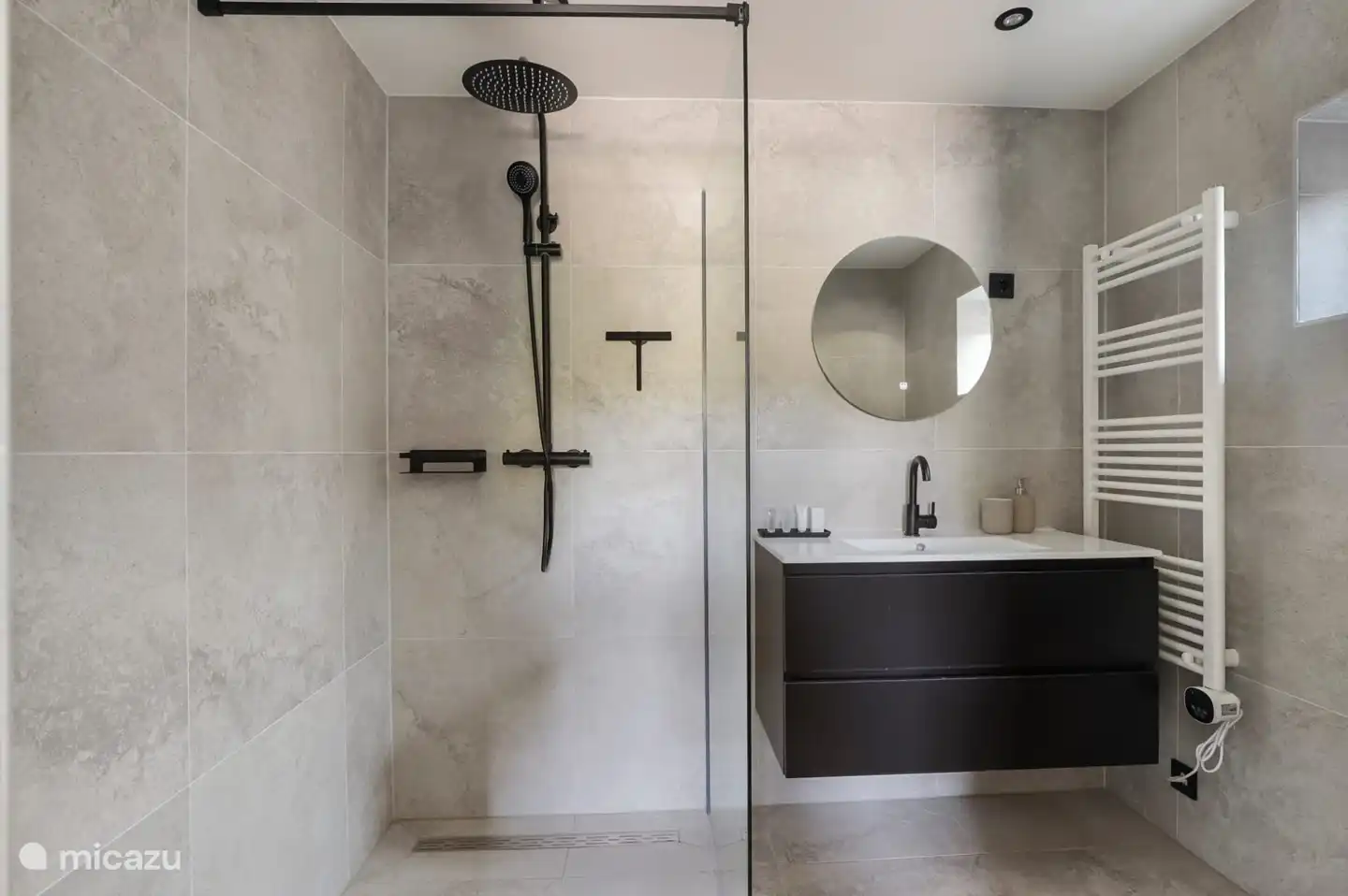 Geräumiges Badezimmer mit ebenerdiger Dusche, Waschbecken und Toilette.