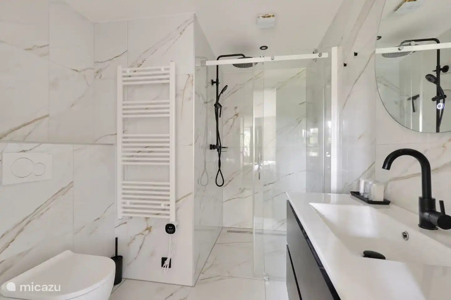 Geräumiges Badezimmer mit ebenerdiger Dusche, Waschbecken und Toilette.