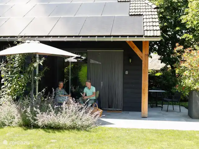 Le rêveur | Pays-Bas, Brabant-Septentrional,  Wilbertoord - maison de vacances Le siège douillet sous l’auvent qui fournit de l’ombre avec le parasol.