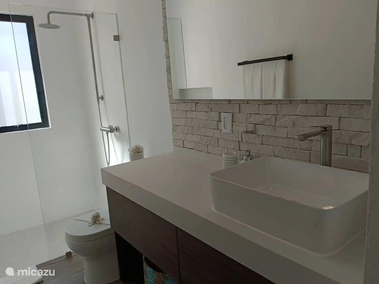 Das Badezimmer verfügt über ein geräumiges Waschbecken, einen großen Spiegel, eine Toilette und eine Regendusche. Außerdem stehen ein Fön und herrlich weiche Handtücher zur Verfügung.