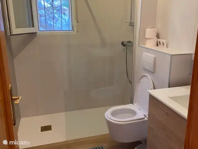 Location de Vacances Espagne, Costa Blanca, Pedreguer, villa - Casa Vista al Mar Salle de bain au rez-de-chaussée.
Douche à l’italienne, toilettes et lavabo avec meuble vasque, miroir avec lumière intégrée, tabouret, corbeille, radiateur sèche-serviettes, sèche-cheveux.