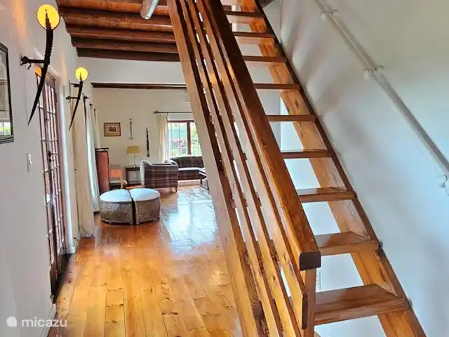 Location de Vacances Afrique du Sud, Le Cap (Cap occidental), Somerset West, gîte / cottage - Chaumière Somerset Ouest Escalier menant au premier étage jusqu'au palier avec sièges et TV, 2 chambres et salle de bain avec baignoire, lavabo et WC.