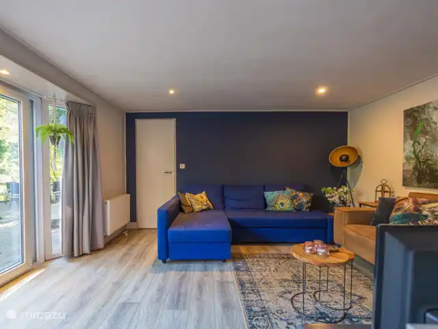 chalet huren in Nederland, Gelderland, Doornspijk – De Eekhoorn M20 Woonkamer met schuifpui, televisie met Netflix, ruime bankstellen en lekker licht. (vloerkleed kan verwijderd worden wanneer u met hond(en) komt.