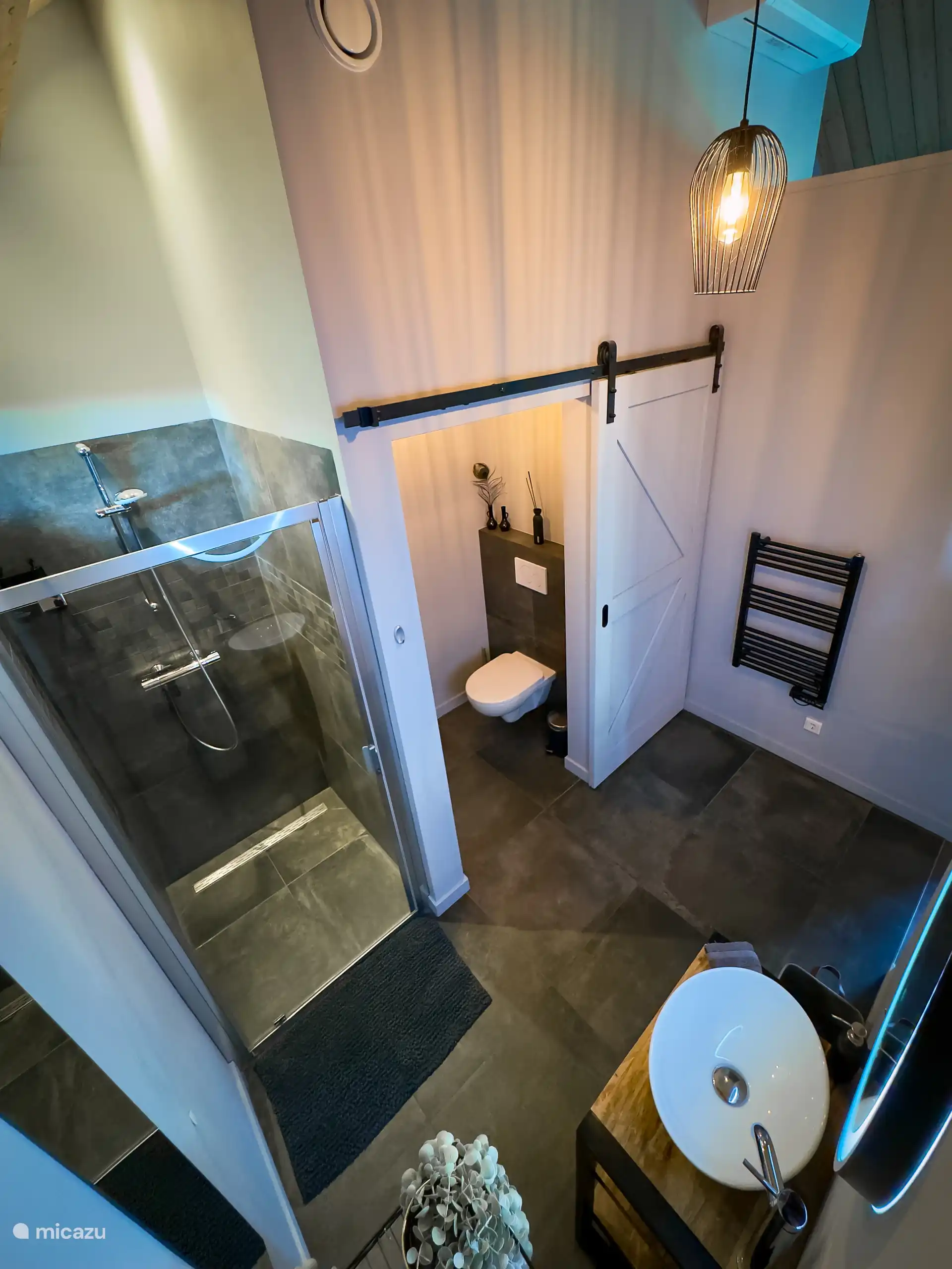 Baño moderno espacioso con ducha con champú y gel de ducha y inodoro independiente