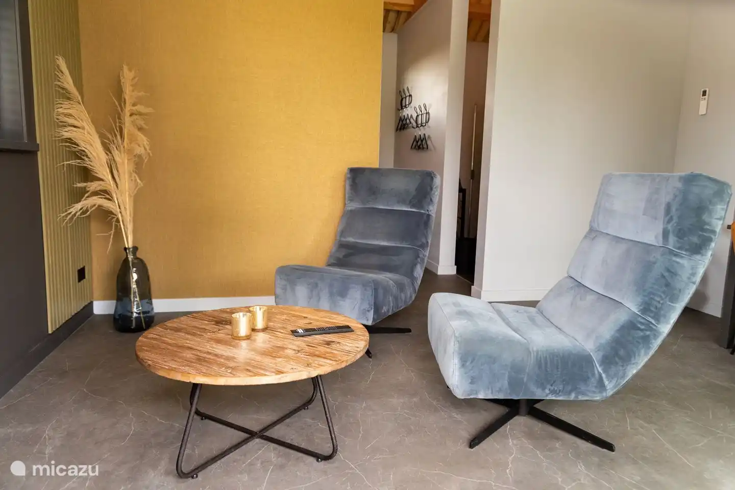 Schöne Sessel im geschmackvoll eingerichteten Wohnzimmer mit Smart-TV und Blick durch die großen Gartentüren auf die Terrasse.