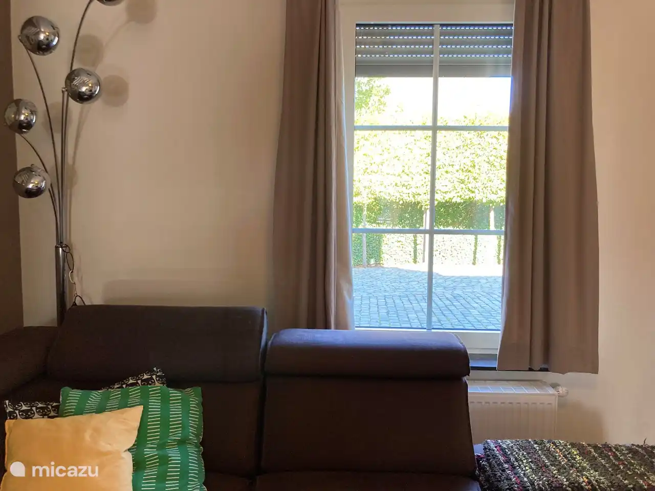 Door het raam zie je de parkeerplaatsen voor het huis voor  2 personenwagens