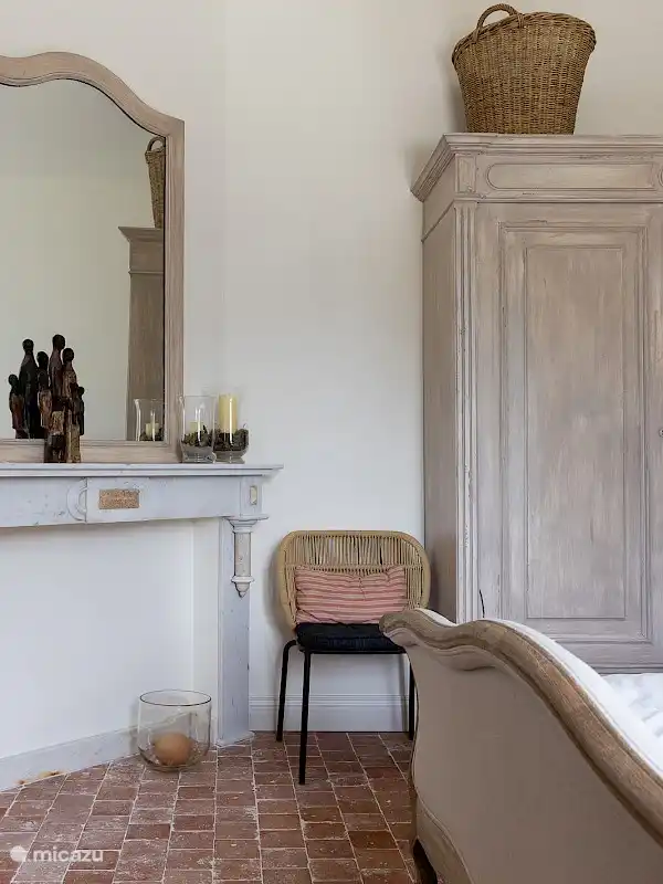The bedroom on the ground floor with old fireplace and impressive mirror.