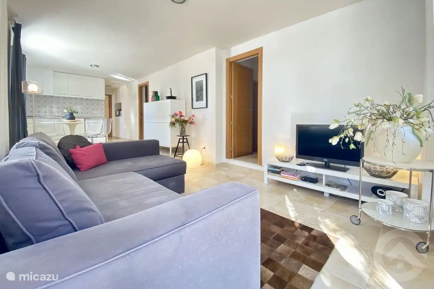 Wohnzimmer im Erdgeschoss mit Sofa und TV. Esstisch neben der Küche