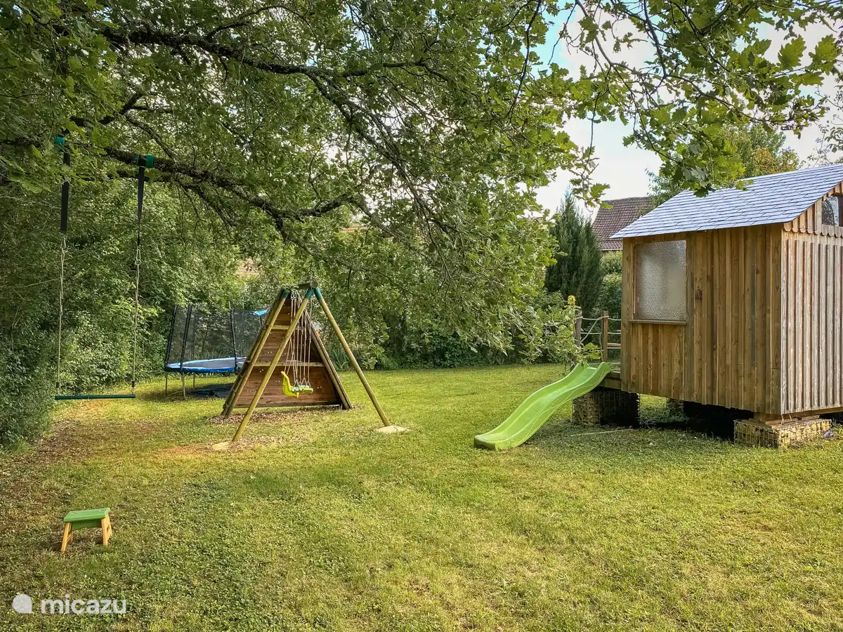 Parque infantil con columpios, tobogán y cama elástica