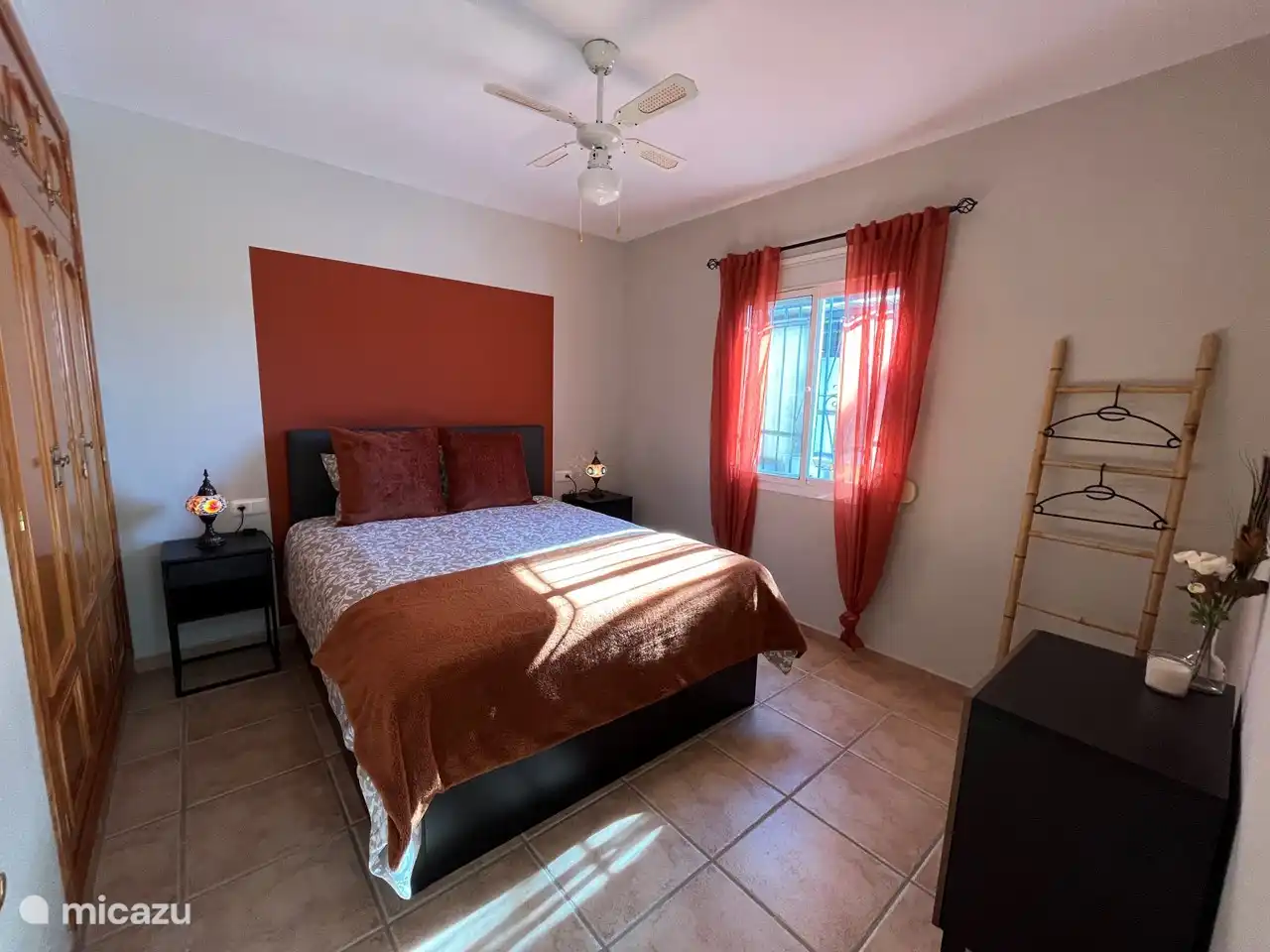 De met zorg ingerichte oranje slaapkamer straalt warmte en comfort uit. De muren zijn gehuld in een rustgevende oranje tint. In het midden van de kamer prijkt een comfortabel tweepersoonsbed, omringd door zachte kussens en een warm deken. 