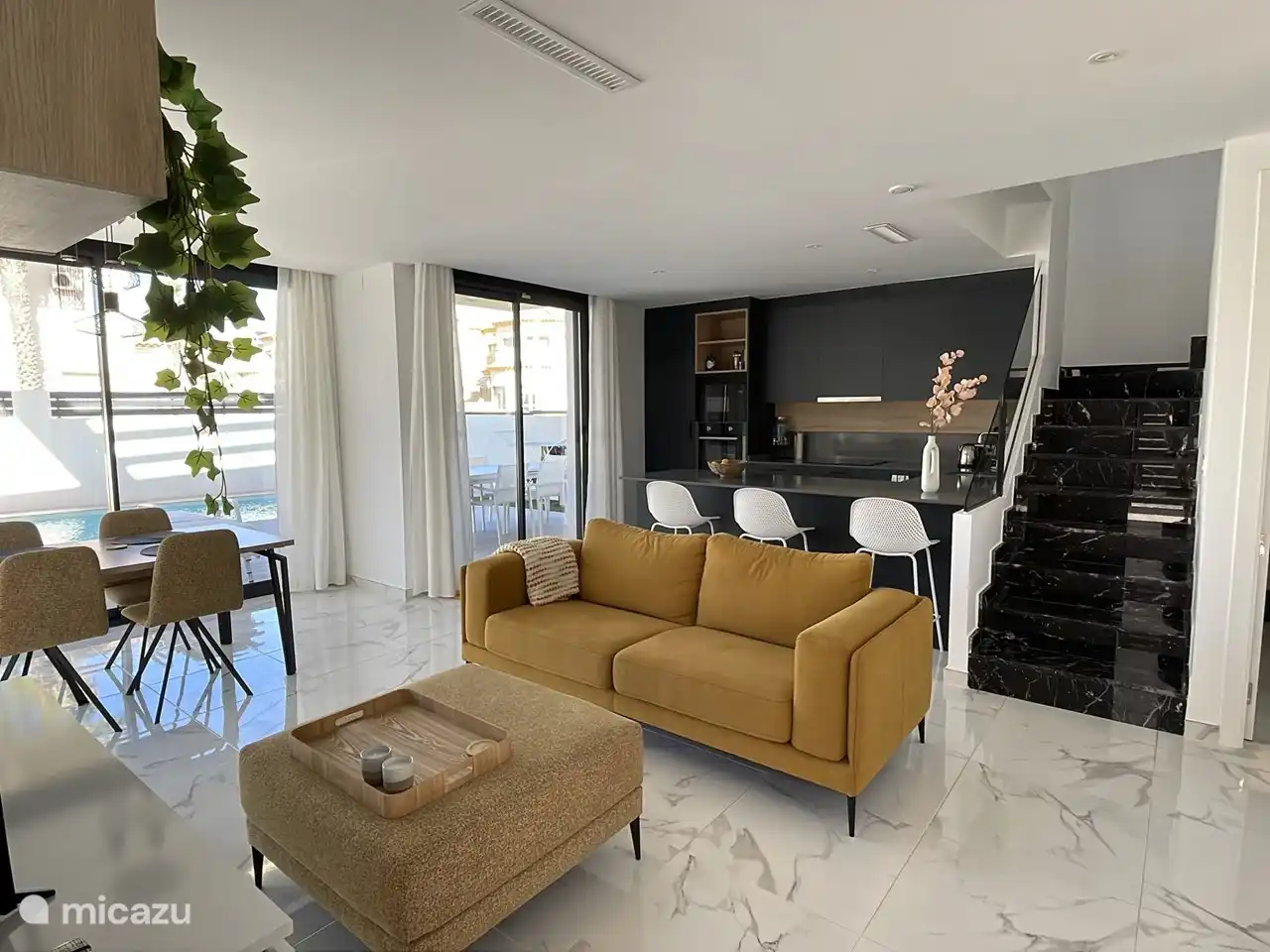 Wohnzimmer und offene Küche. Inklusive einer bequemen 3-4-Personen-Couch, TV, Esstisch (ausziehbar) sowie einer Bar. Das Wohnzimmer bietet Zugang zum Schlafzimmer im Erdgeschoss und zum separaten Bad/Waschraum.