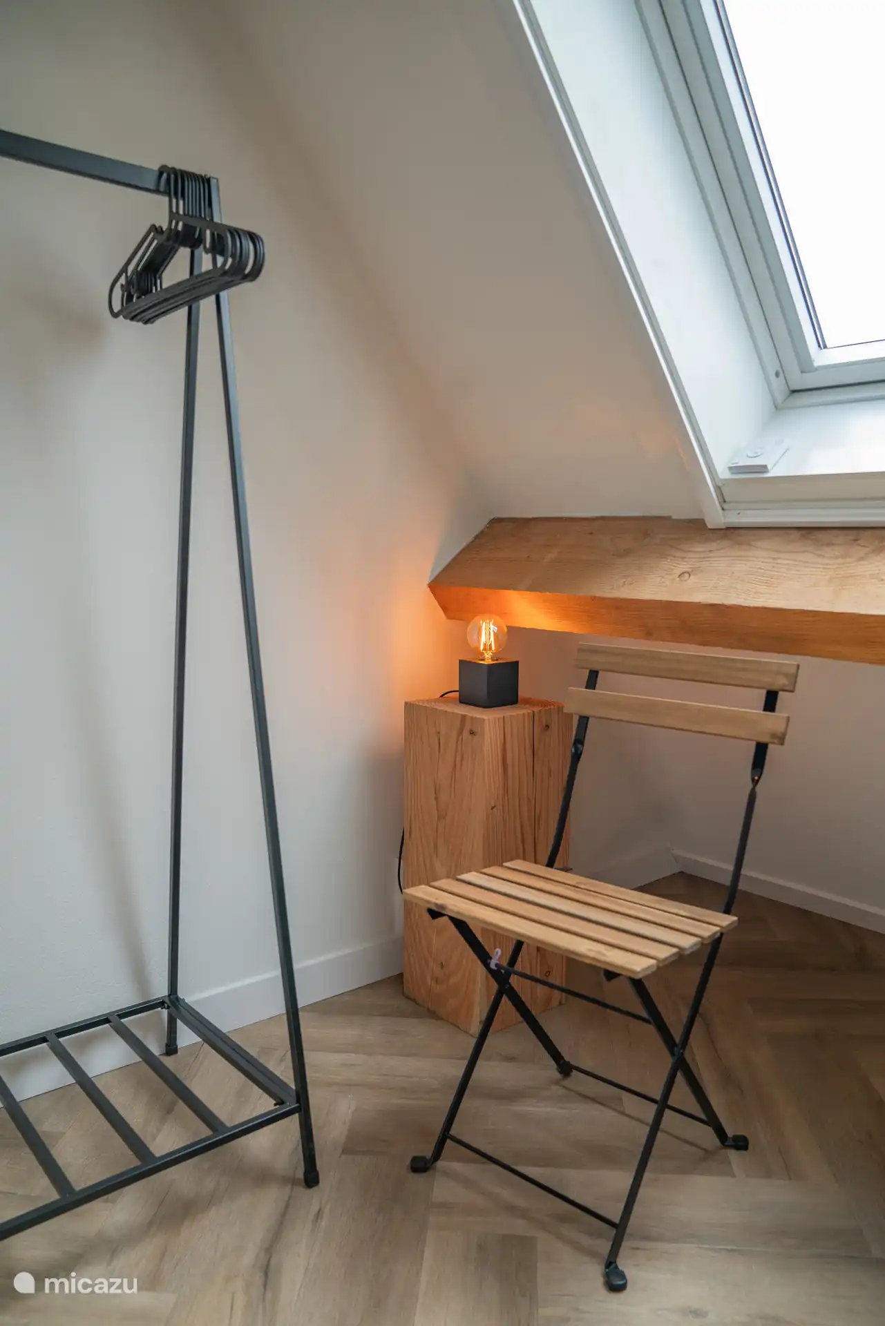 Dormitorio 1 con perchero y silla plegable.