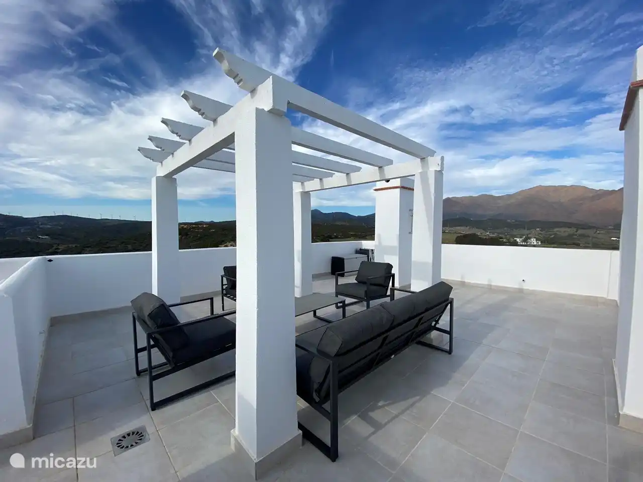 Eine große Dachterrasse mit Loungebereich, Sonnenliegen und Außendusche. Von der Dachterrasse hat man einen wunderschönen Blick über die Bucht von Estepona, die Berggipfel und man kann Gibraltar und Marokko sehen.