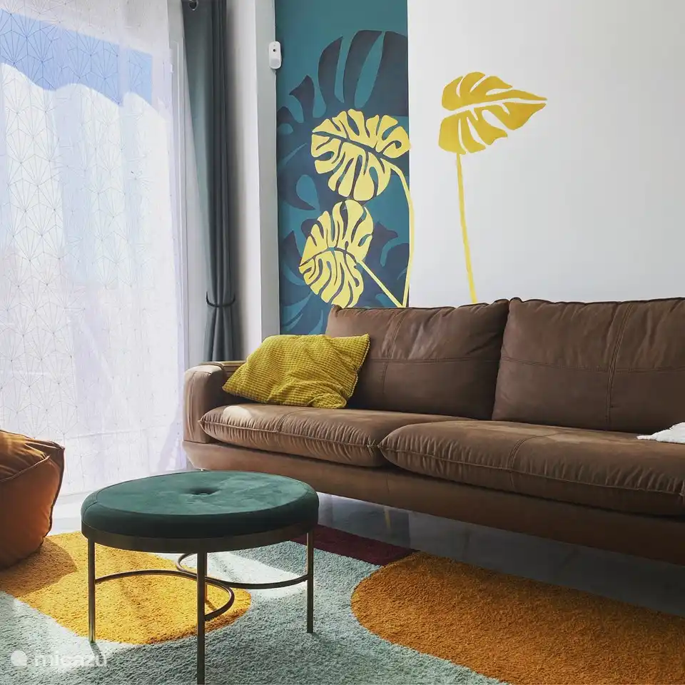 Ein selbst gestaltetes Wandgemälde verleiht dem Wohnzimmer einen warmen Charakter.