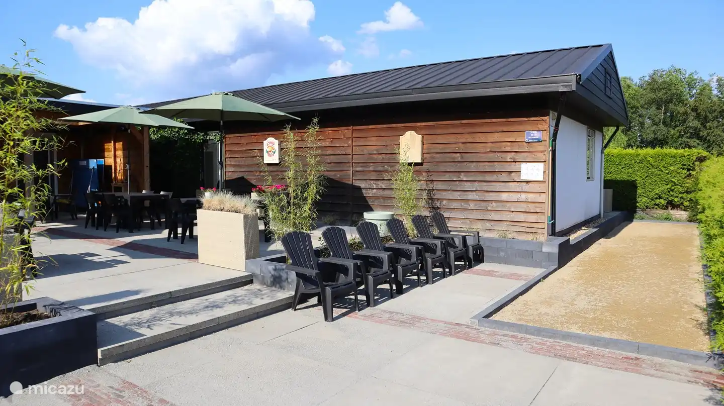 Jardin avec auvent, table de ping-pong, jeu de boules, trampoline et jeu de fléchettes.