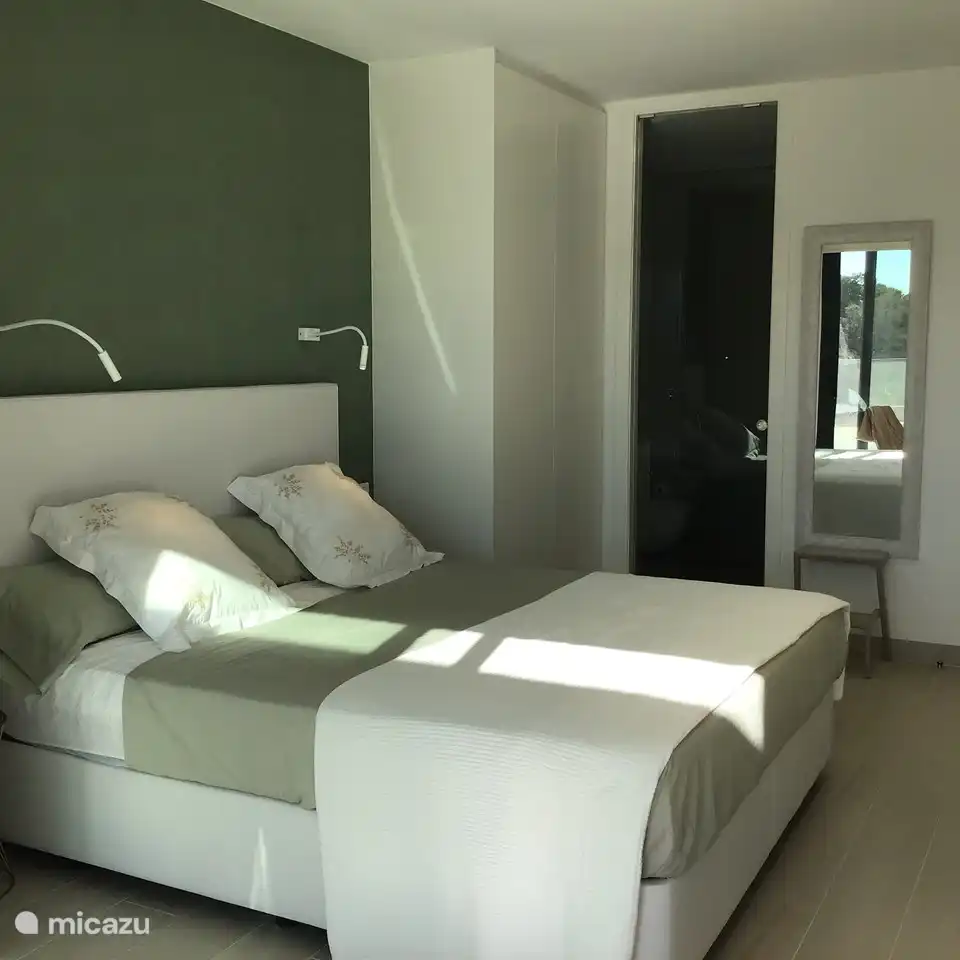 Grande chambre 1, vue côté terrasse, armoire 2, miroir et vue sur la salle de bain communicante avec porte vitrée