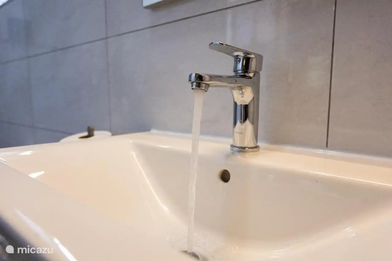 Op de eerste verdieping bevindt zich een ruime badkamer, voorzien van een heerlijke regendouche met warm water(heater), een wastafel en een toilet.