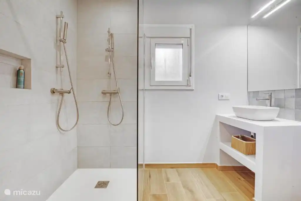 Badezimmer mit Doppeldusche, WC und Waschbecken.