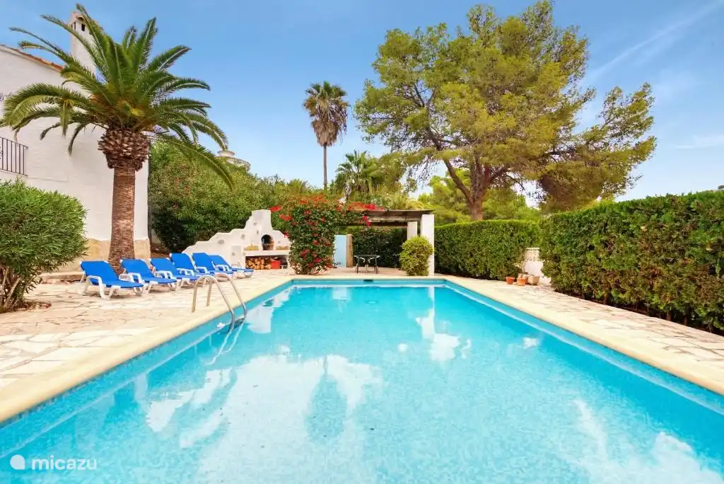 Blick auf den Pool mit überdachter Terrasse im Anbau und Außendusche