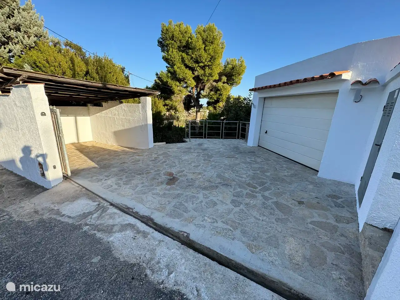 Vue sur le carport, l'aire de stationnement et le garage fermé.