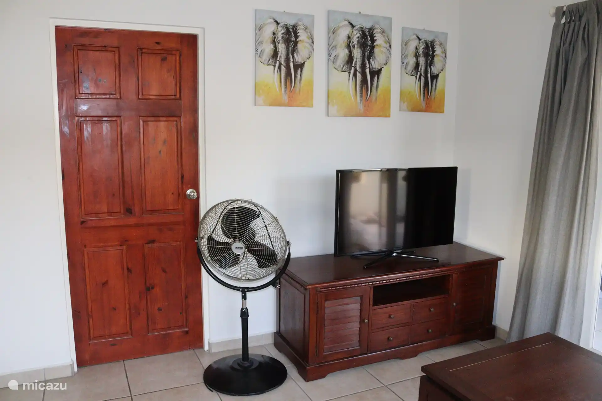The living room, equipped with a television and fan. There is also air conditioning