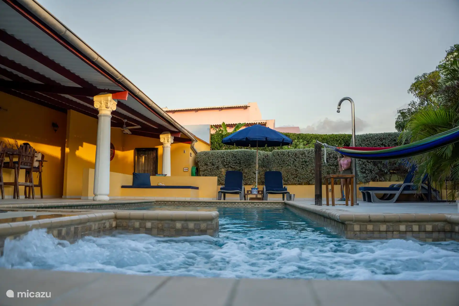 Enjoy ultimate poolside relaxation surrounded by comfortable sun loungers, a hammock, and a shaded umbrella.