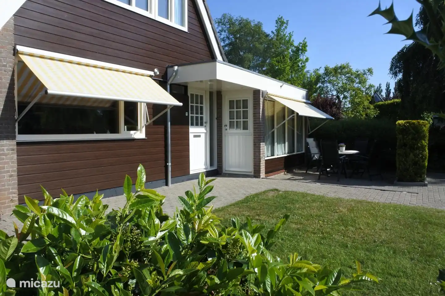 Links is de deur naar het huis en rechts naar de studio. Beide hebben zonneluifels. Voor de studio is een apart terras.