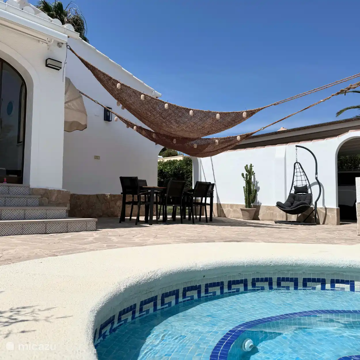 Terraza con manteles de sombra y mesa de comedor con 6 sillas.