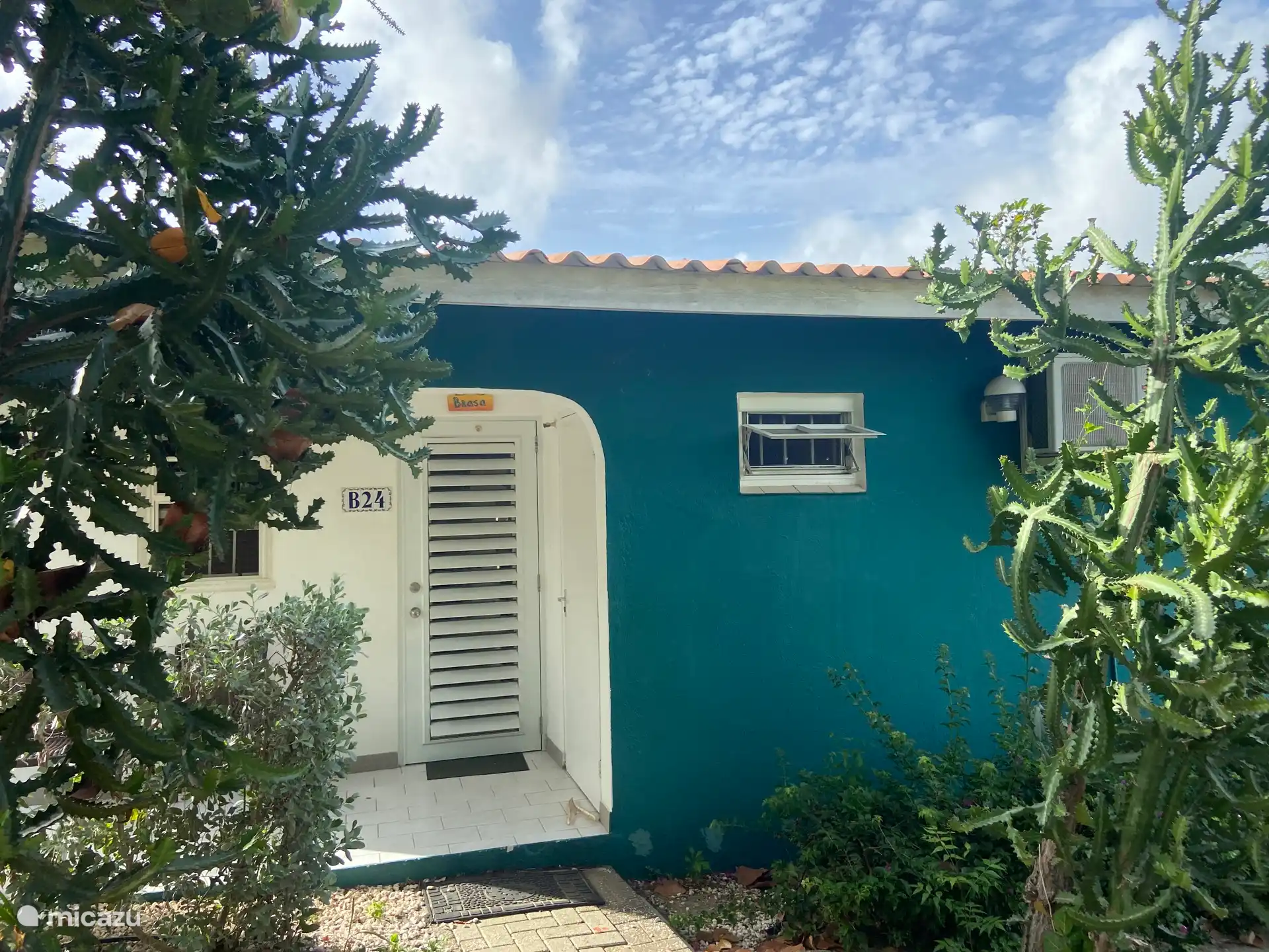 La entrada cubierta del bungalow Brasa con dos sillas para sentarse frente a la casa.