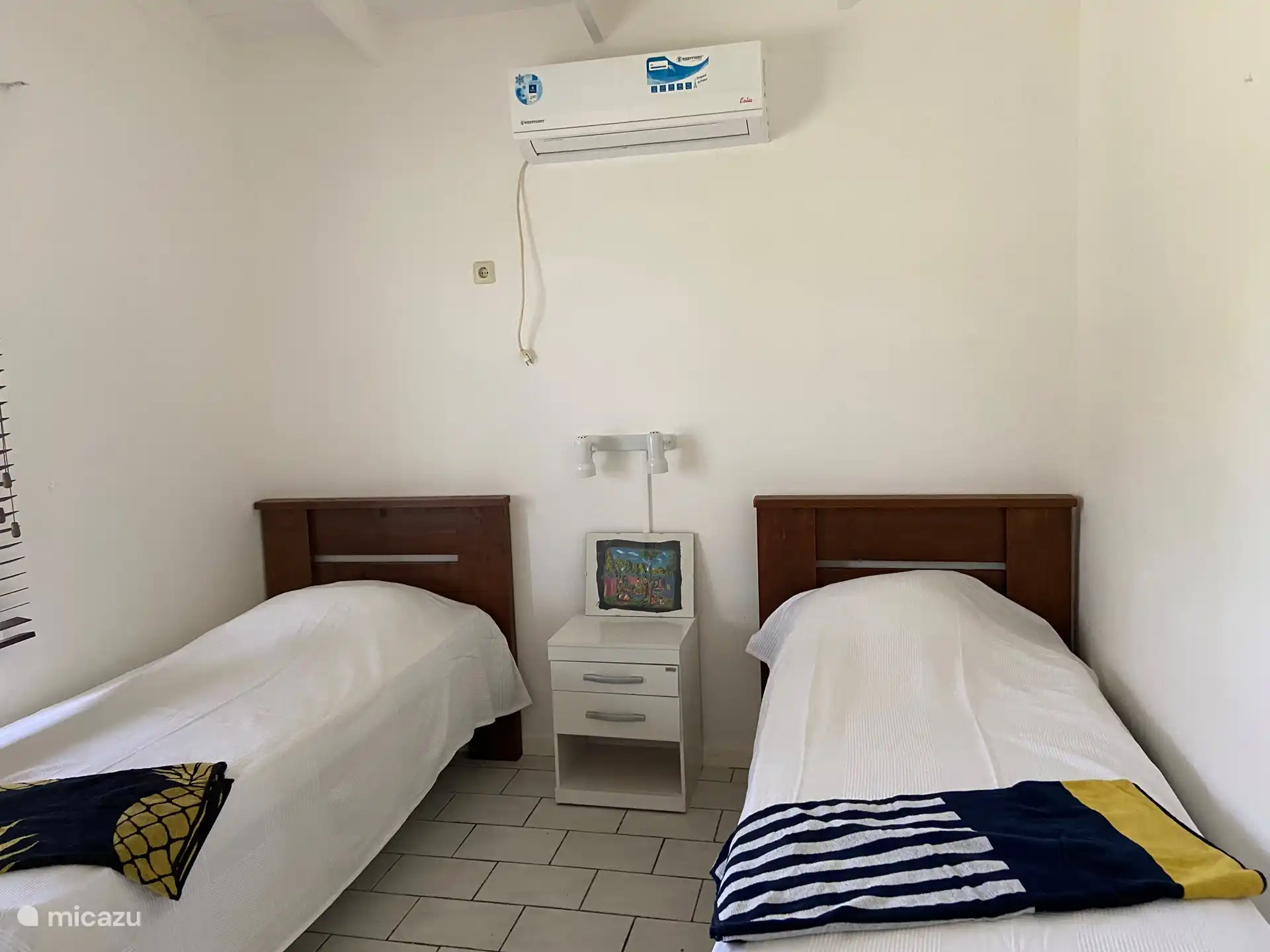 segundo dormitorio con dos camas separadas, mesita de noche, aire acondicionado, armario empotrado con ropa de cama y toallas de playa.