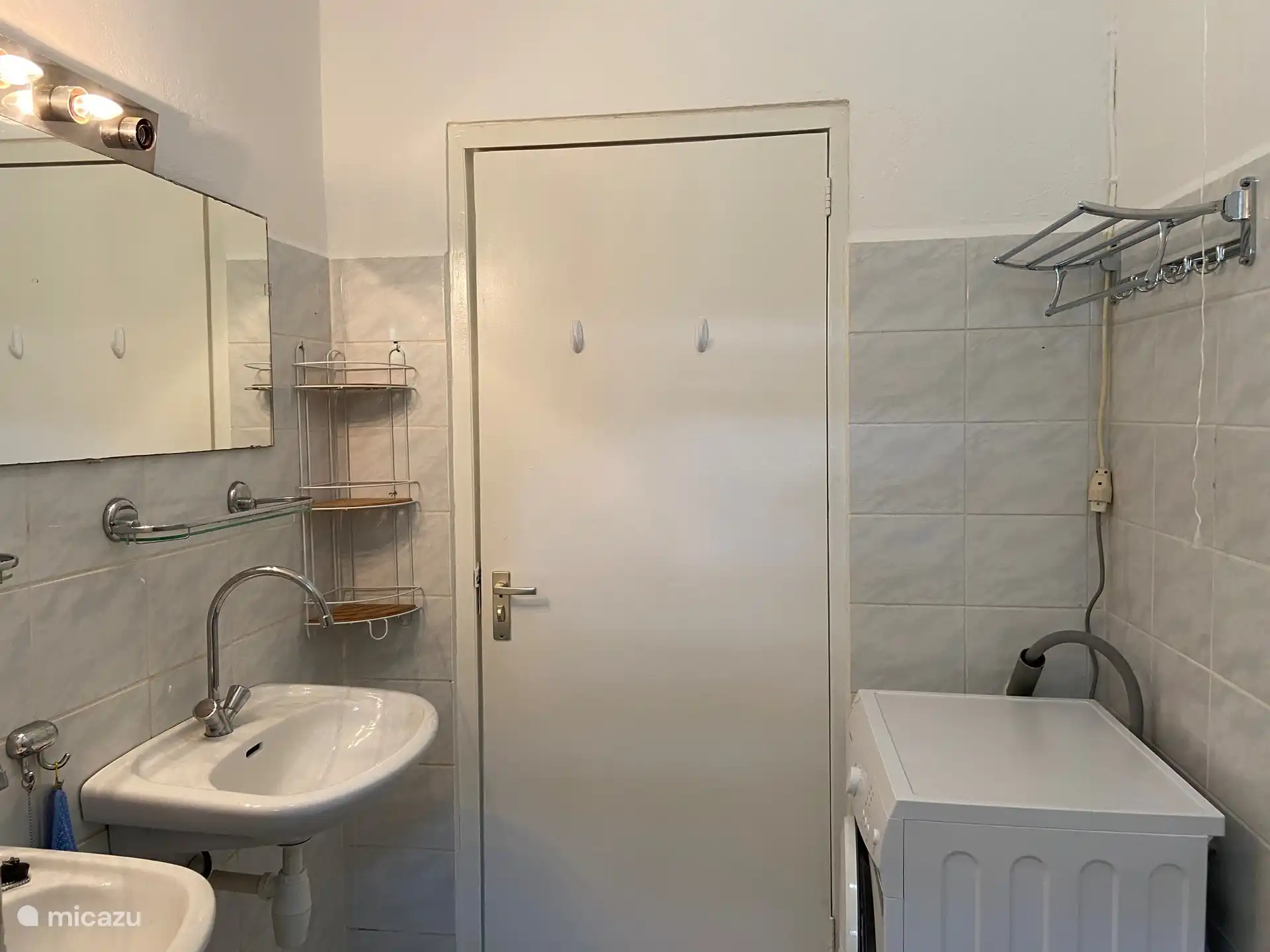 Baño con dos lavabos, WC y lavadora.