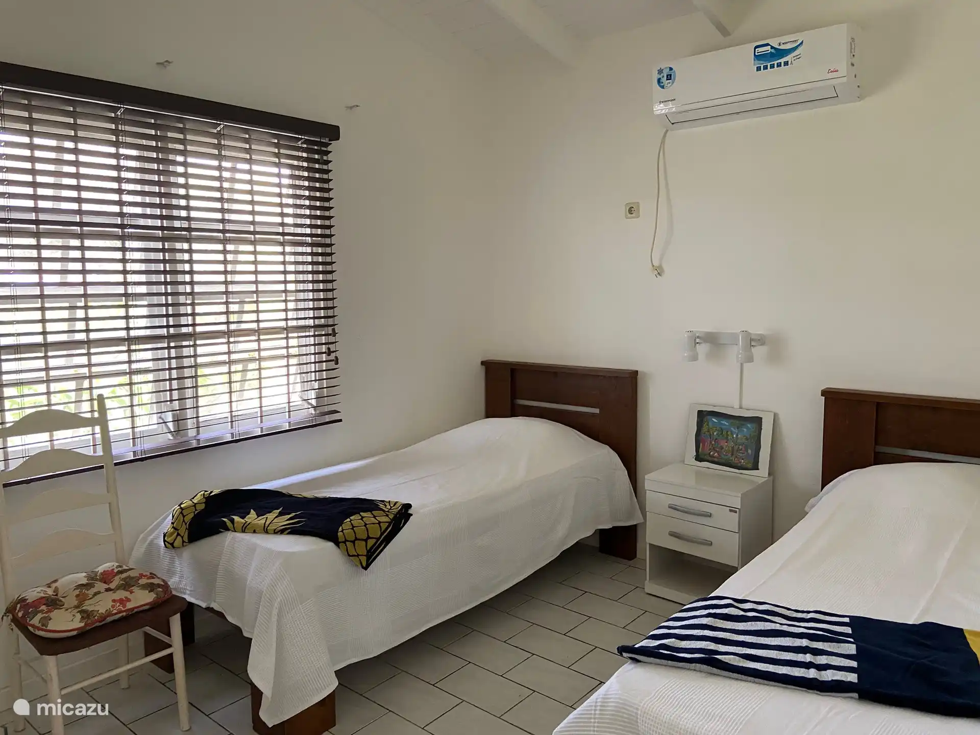 segundo dormitorio con dos camas separadas, mesita de noche, aire acondicionado, armario empotrado con ropa de cama y toallas de playa.