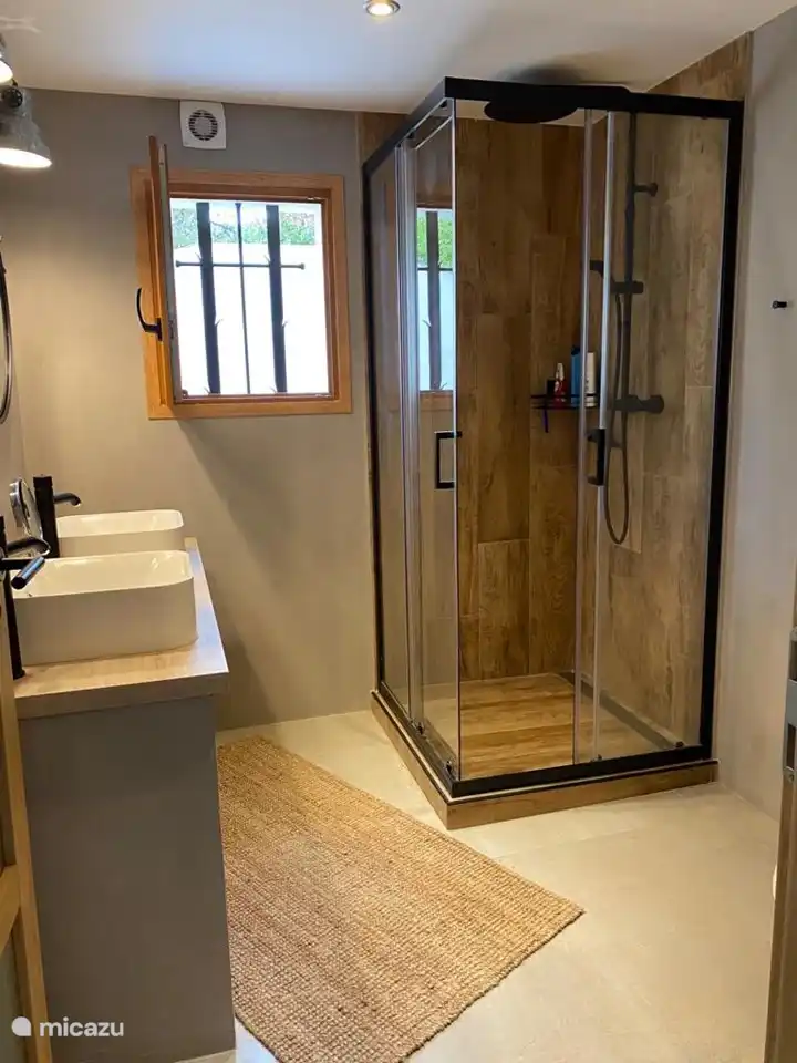 Badezimmer mit Doppelwaschbecken, Regendusche und WC.