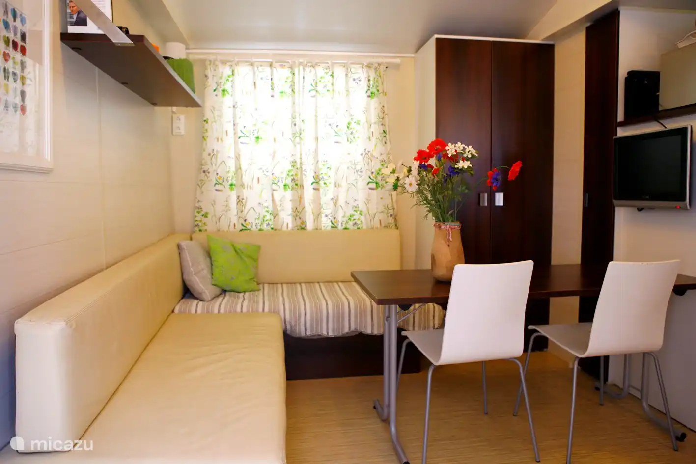 Sala de estar/sala de estar interior con sofá, mesa, sillas y televisión.