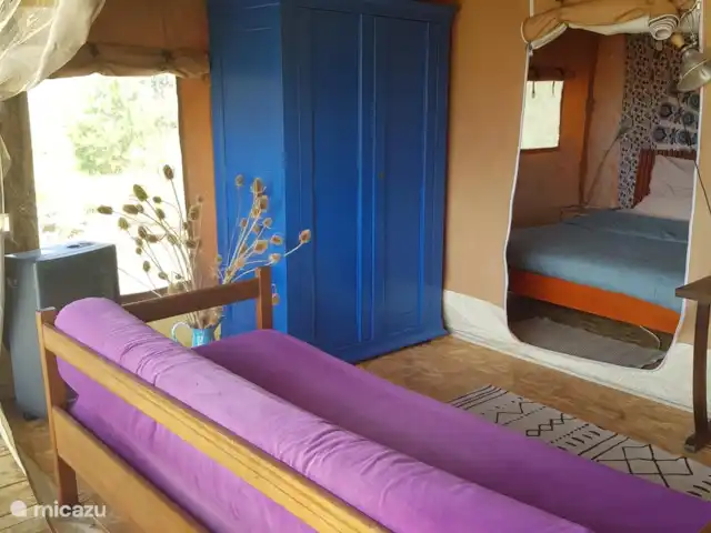 glamping / safaritent / yurt huren in Frankrijk, Aude, Montjardin – Courtizaire du Haut (slaap)bank die afhankelijk van het weer naar binnen gekeerd of naar buiten gekeerd kan worden. Bank die als 5e prs slaapbank gebruikt kan worden. Ook kan in plaats van de slaapbank, een opklapbed tussen de 2 losse bedden geplaatst worden. Let wel: weinig tot geen loopruimte in dat laatste geval.