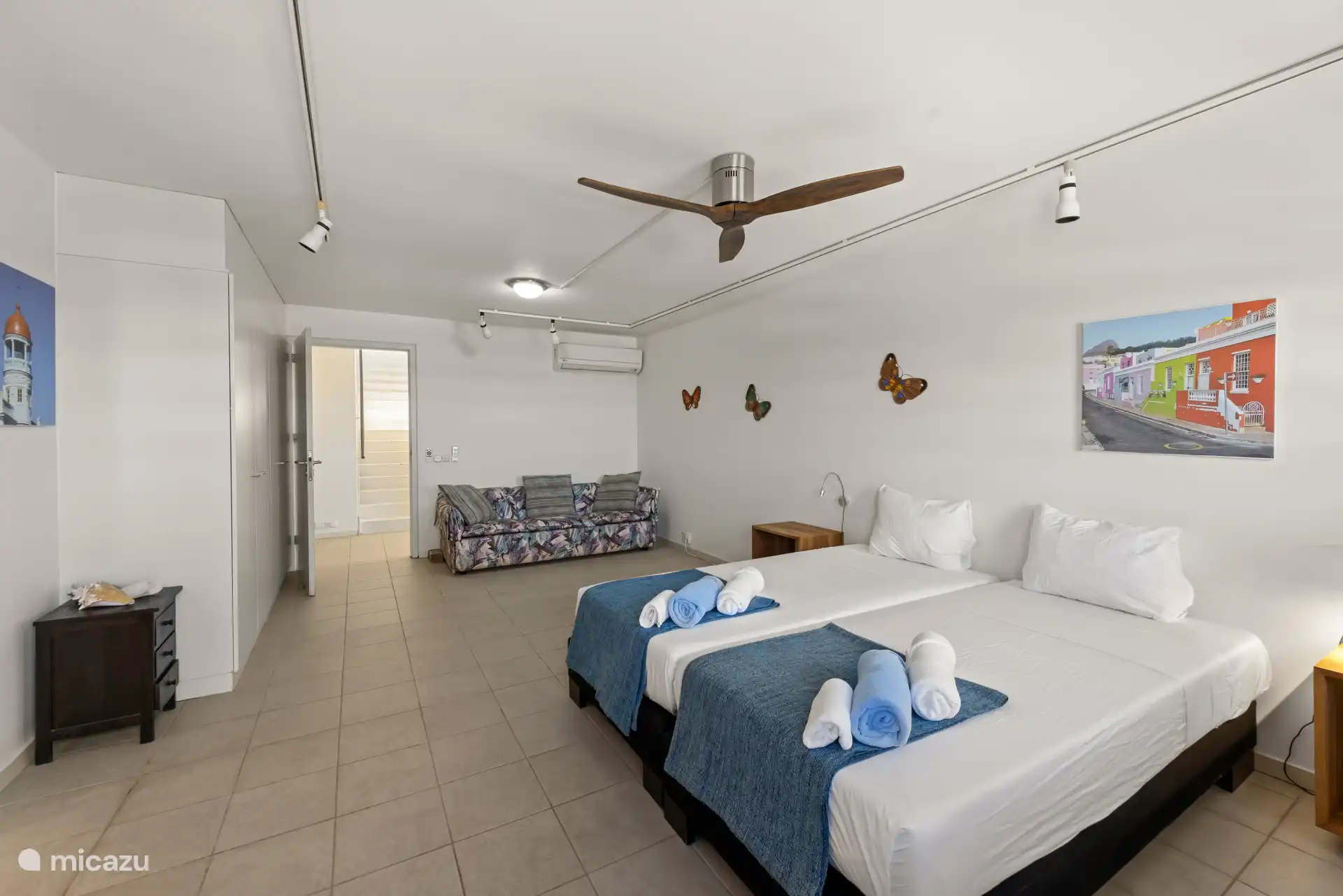 Cette chambre possède aussi un canapé et un ventilateur de plafond.