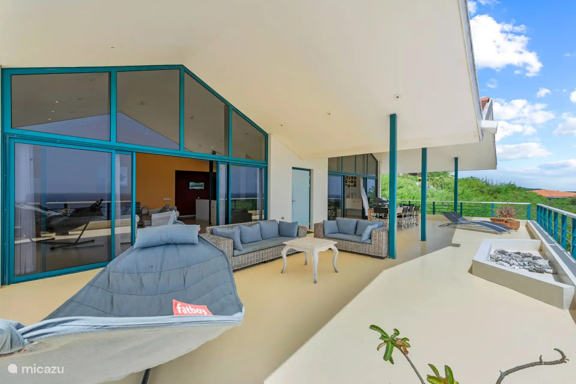 Geräumige schattige Veranda mit Sitz- und Essbereich und 180-Grad-Blick auf das Meer.