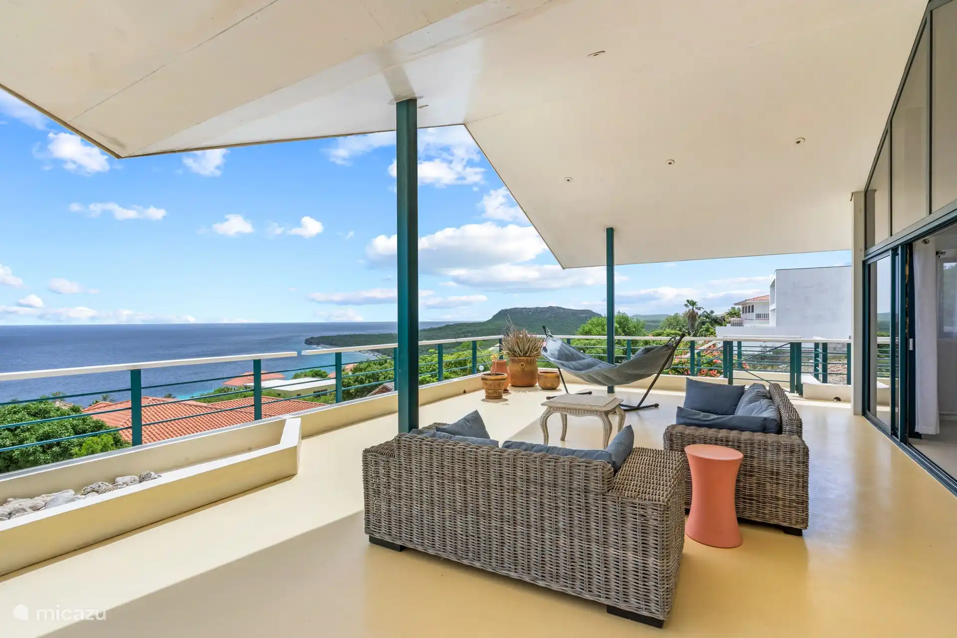 Geräumige schattige Veranda mit Sitz- und Essbereich und 180-Grad-Blick auf das Meer.