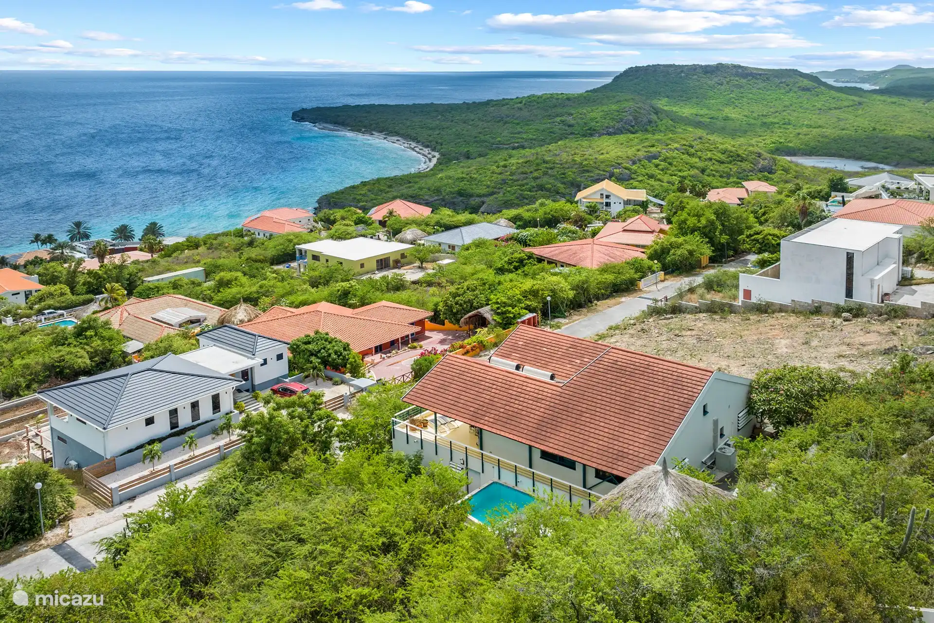 Blick aus der Vogelperspektive über die Villa, Cas Abou, die umliegenden Hügel und das Meer. 