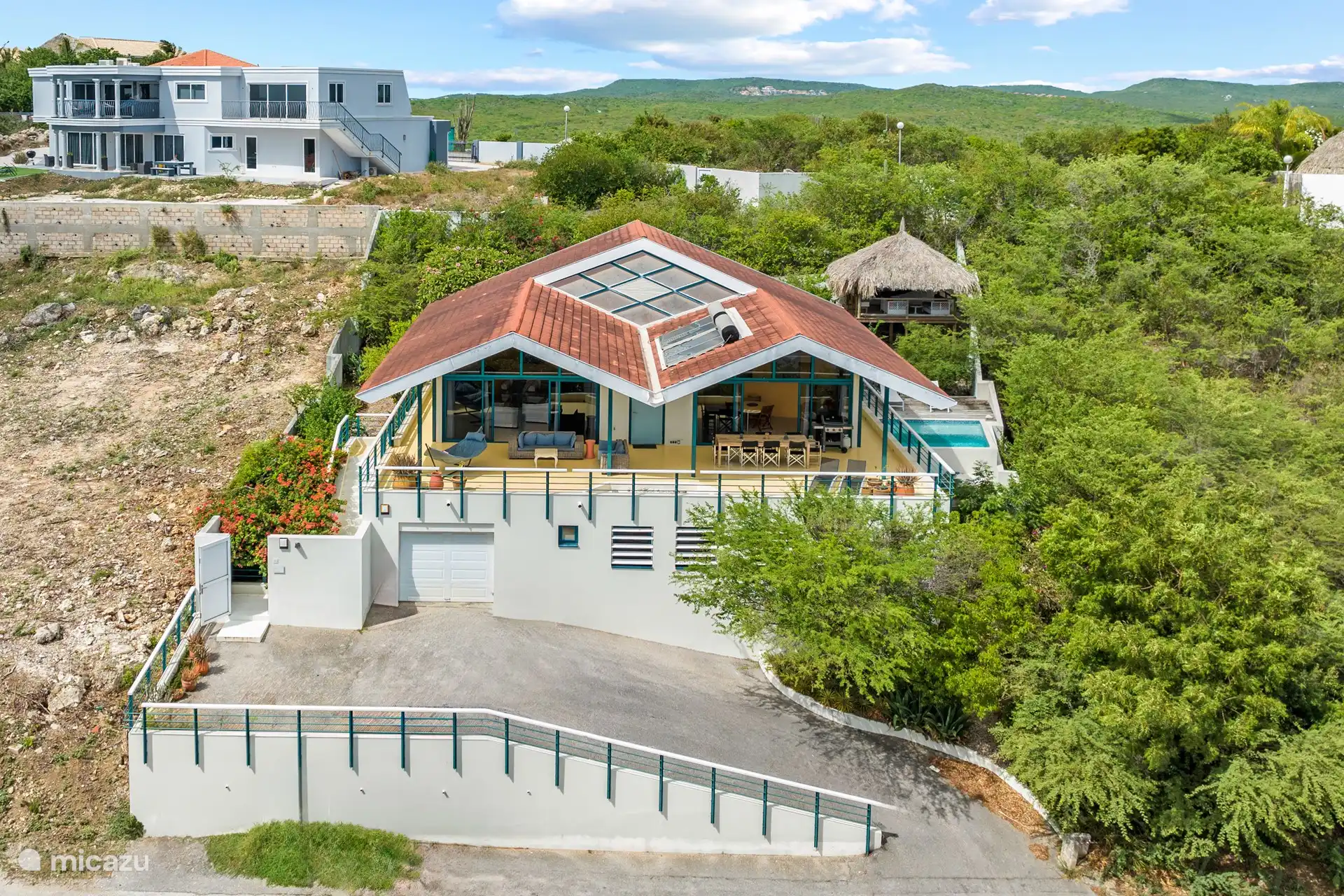 Blick aus der Vogelperspektive über die Villa, Cas Abou, die umliegenden Hügel und das Meer. 