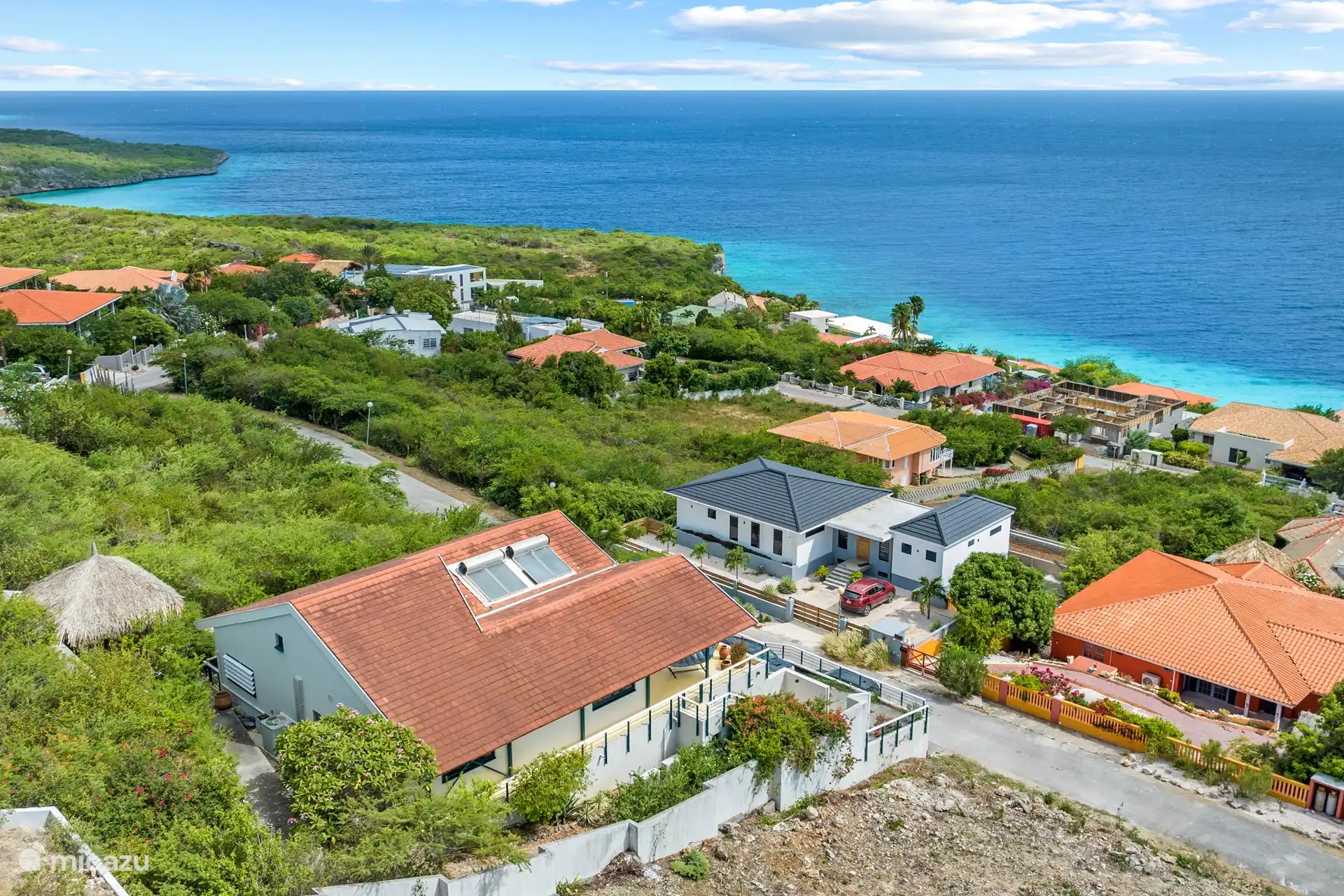 Blick aus der Vogelperspektive über die Villa, Cas Abou, die umliegenden Hügel und das Meer. 