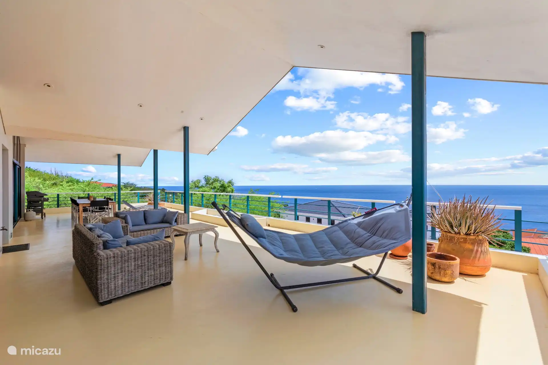 Geräumige schattige Veranda mit Sitz- und Essbereich und 180-Grad-Blick auf das Meer.