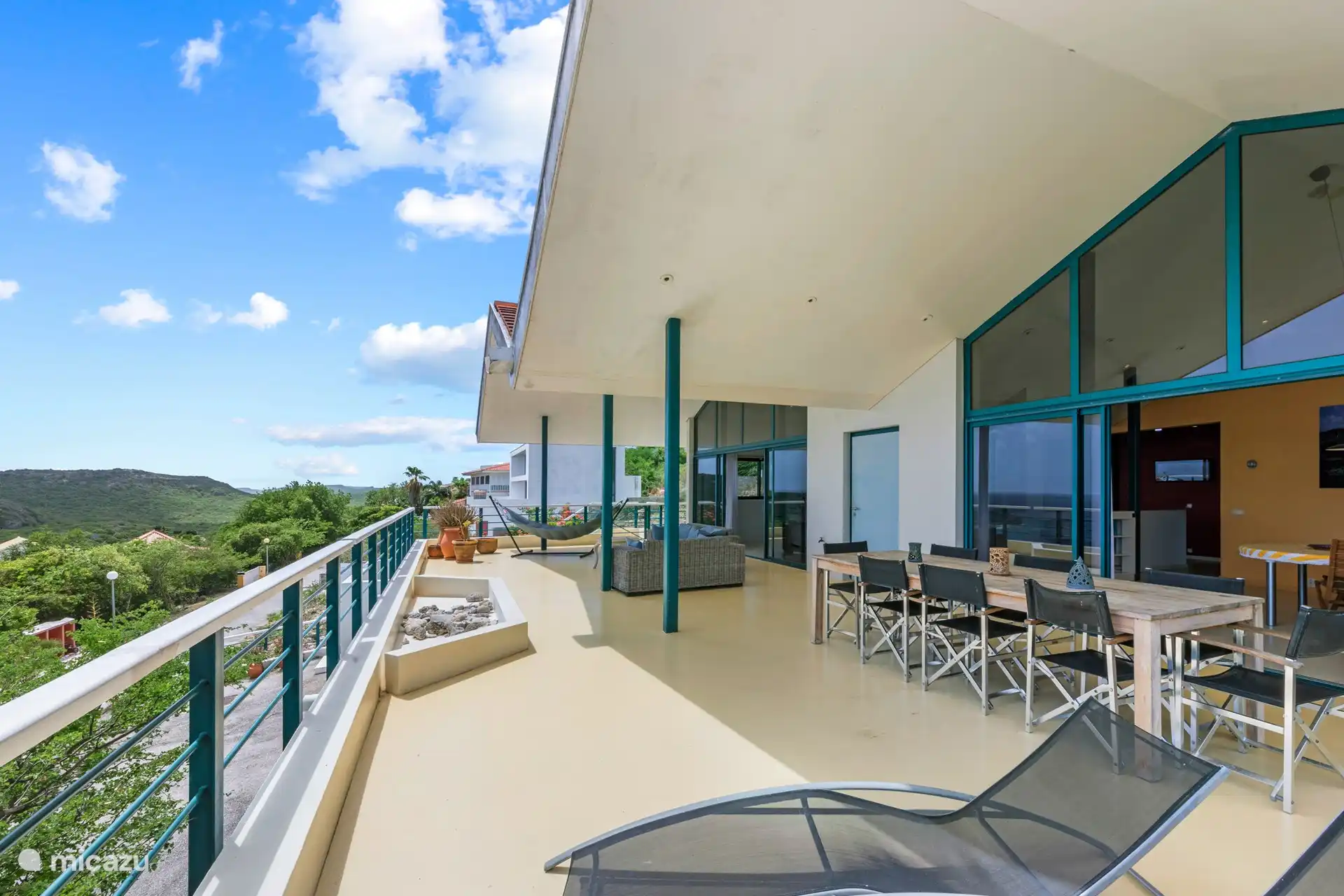 Geräumige schattige Veranda mit Sitz- und Essbereich und 180-Grad-Blick auf das Meer.