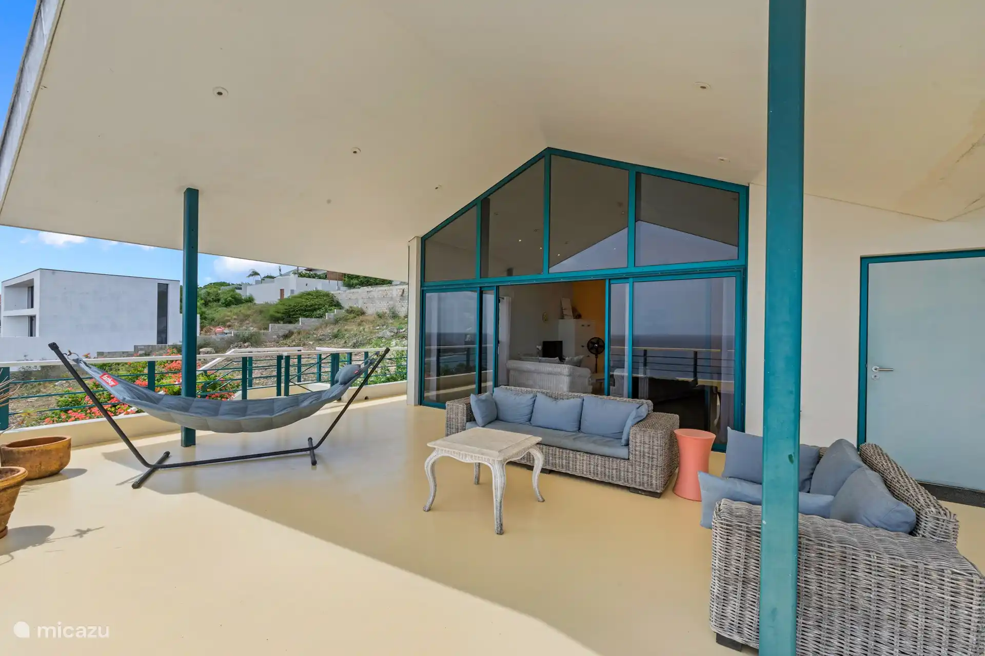 Geräumige schattige Veranda mit Sitz- und Essbereich und 180-Grad-Blick auf das Meer.