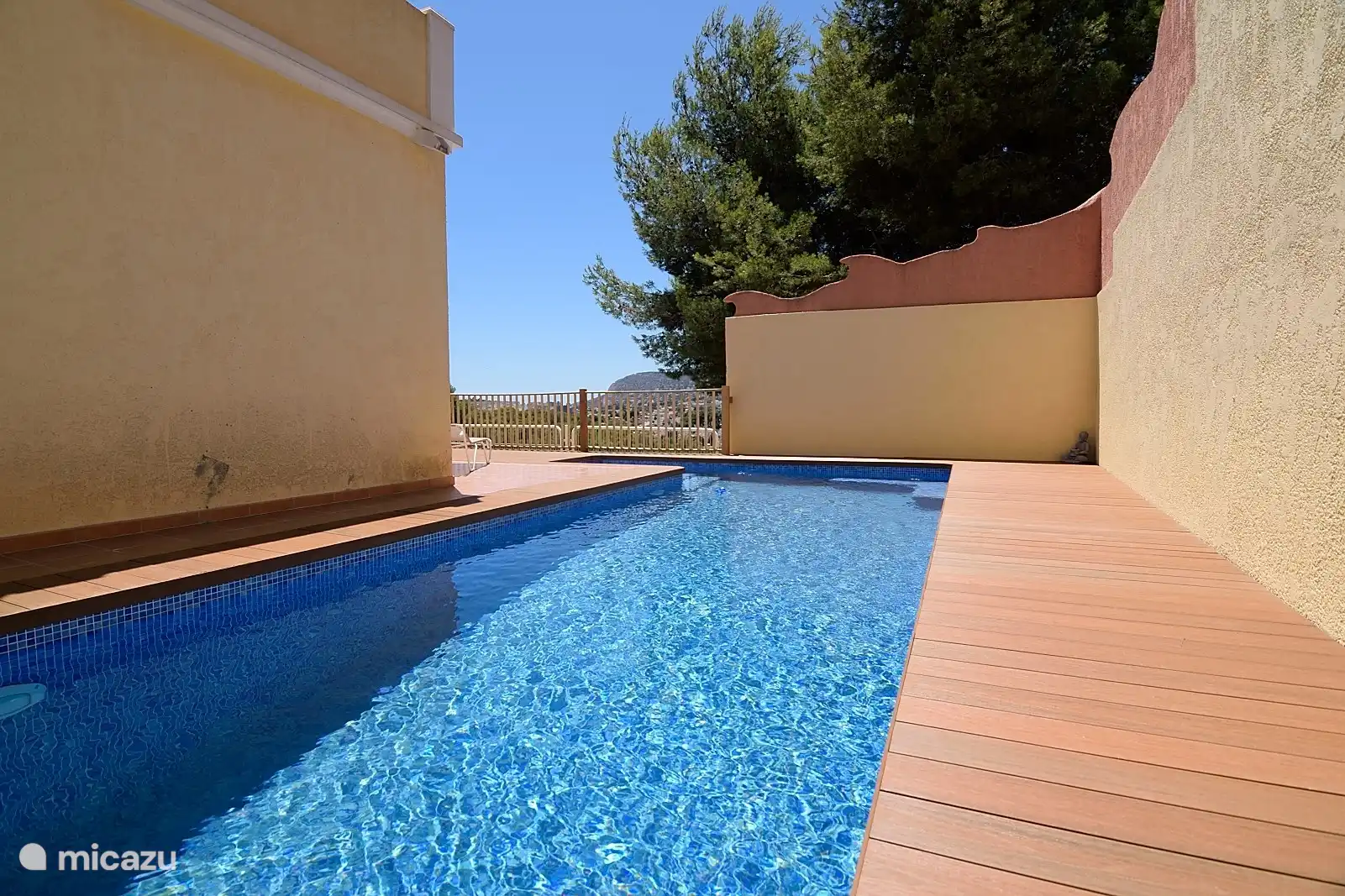 Une nouvelle piscine. Assez long pour nager et faire quelques tours. Et devant vous voyez le jardin avec un grand avocatier et un laurier et quelques plantes en pot. Il a une partie profonde d'un côté. Il y a des escaliers à l'entrée et à l'intérieur un banc pour s'asseoir.