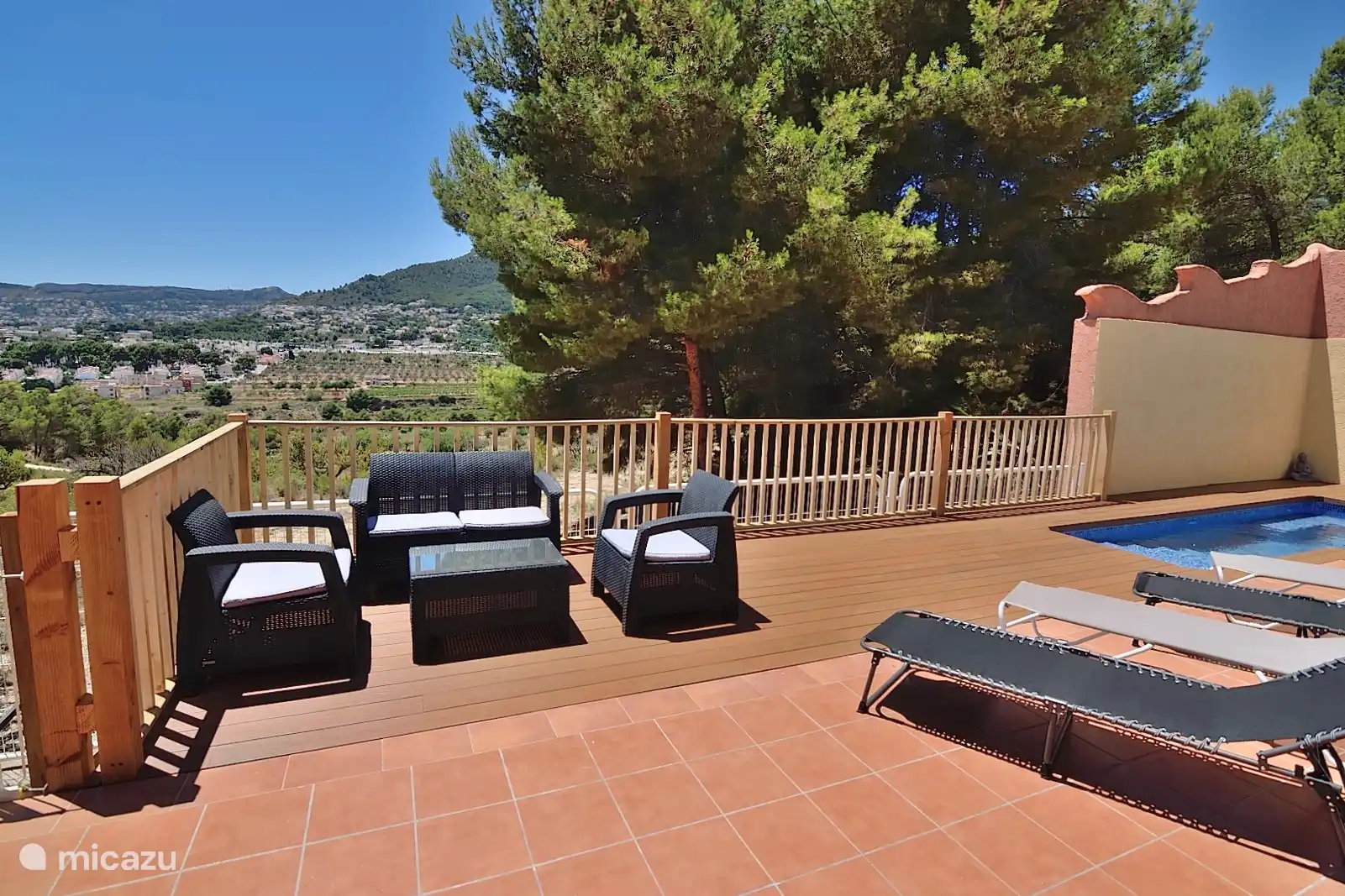 Terrasse avec un canapé, deux fauteuils. avec des coussins et une table avec du verre assorti.